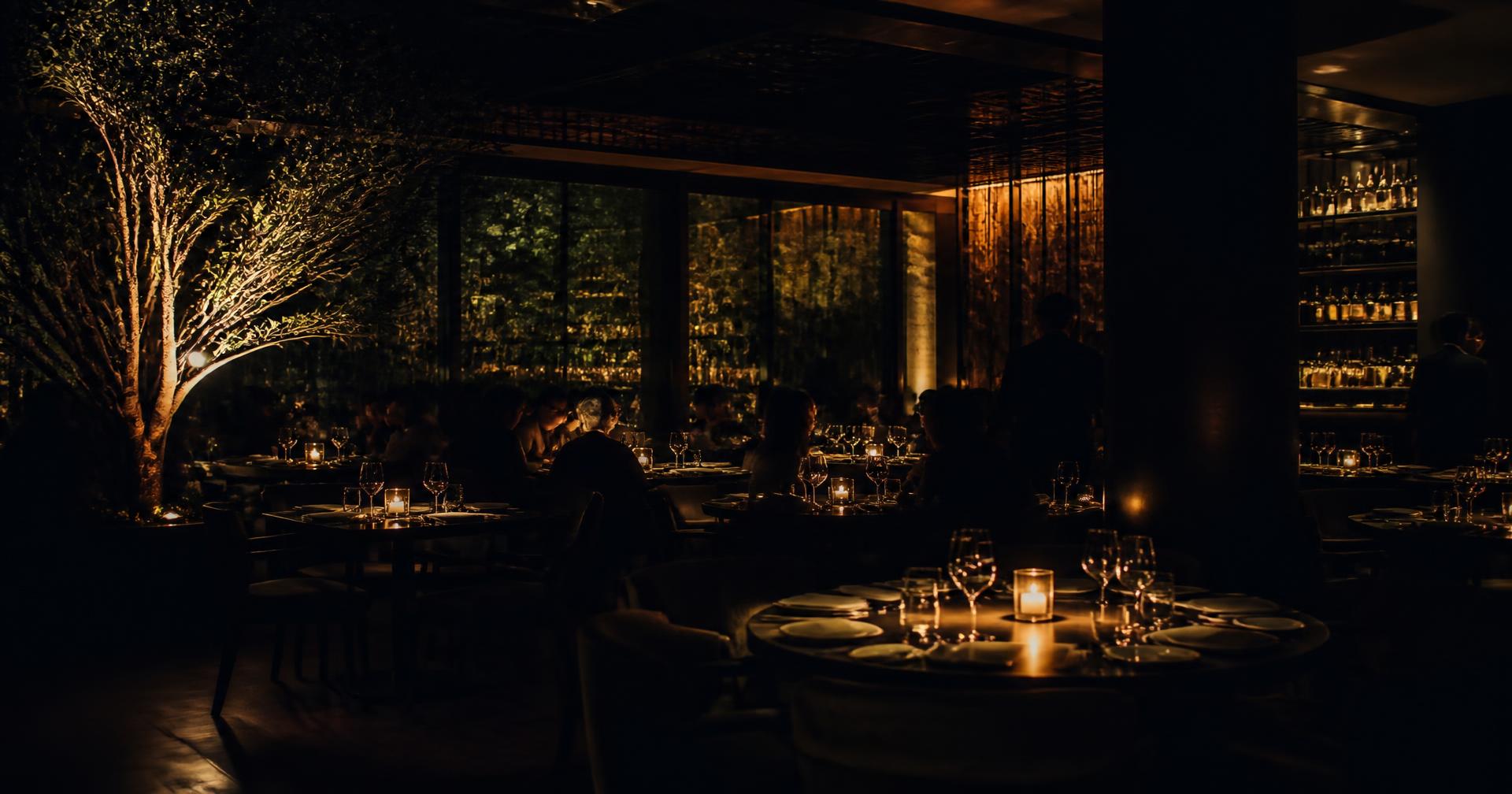 Guests dining by candlelight in the darkened VÉRA dining room